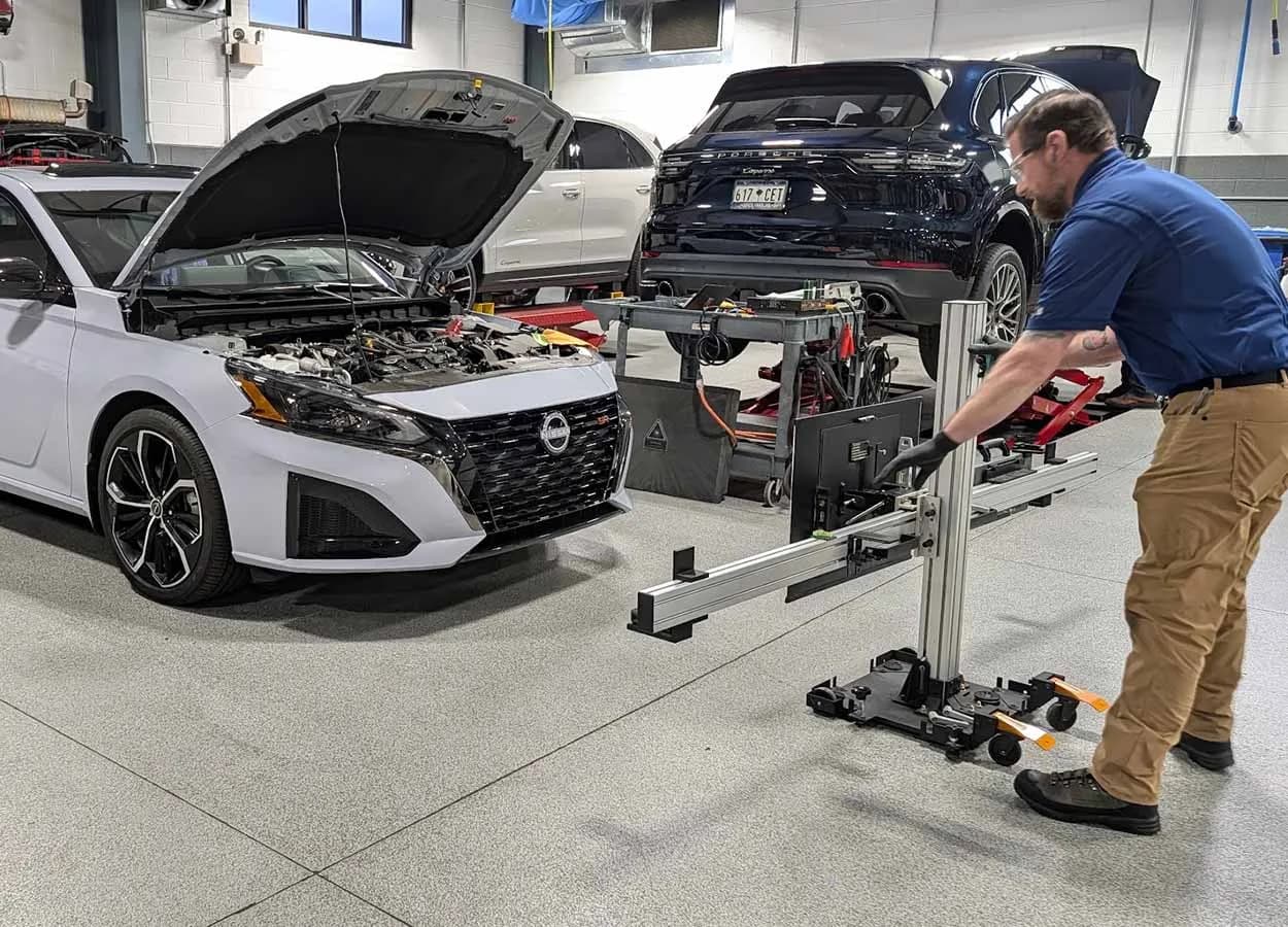 technician setting up an ADAS calibration target rig in front of a vehicle